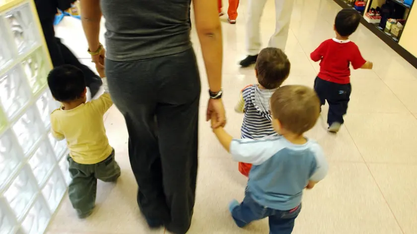 Una maestra accompagna i bambini in una scuola materna