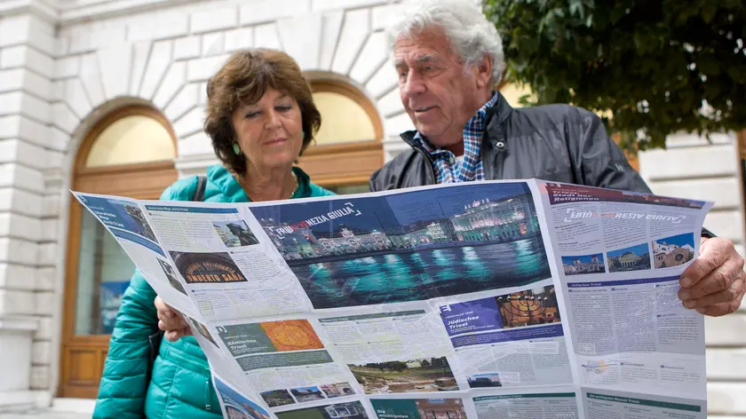 Turisti in piazza dell'Unità davanti alla sede della TurismoFvg