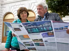 Turisti in piazza dell'Unità davanti alla sede della TurismoFvg