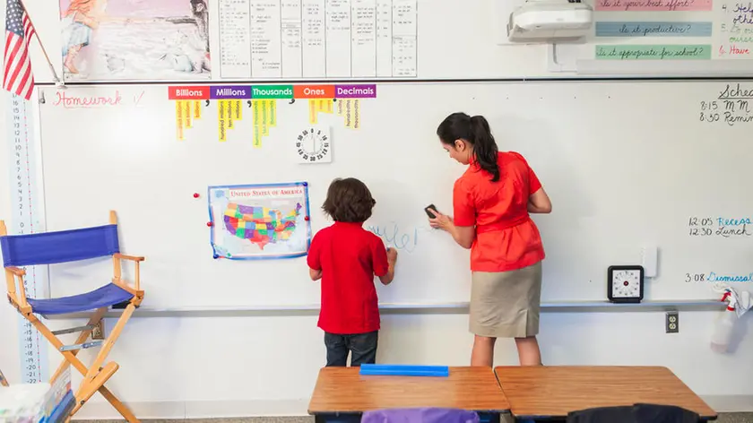 Teacher helping student at whiteboard in classroom