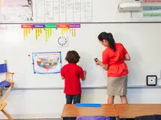 Teacher helping student at whiteboard in classroom