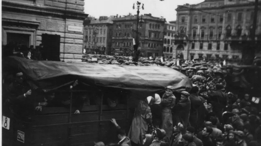 Lo scatto di Attilio Leonardi, colto all'angolo di piazza Unità, testimonia lo slancio con cui i triestini accolsero i bersaglieri che venivano portati in centro sui camion per prepararsi alla sfilata sulle Rive