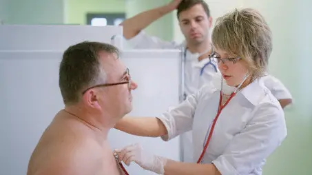 Doctor listening to patient's heart --- Image by © Mika/Corbis