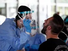 A health worker wearing protective gear takes swab samples from a tourist to test for the coronavirus, at Promahonas border crossing with Bulgaria, which is the only land border into Greece that is open on Monday, July 6, 2020. Dozens of vehicles of Serb holidaymakers who were trapped at the Greek border overnight have been allowed to cross into Greece after a ban on the entry of people from Serbia came into effect due to a coronavirus flare-up in Serbia. (AP Photo/Giannis Papanikos)