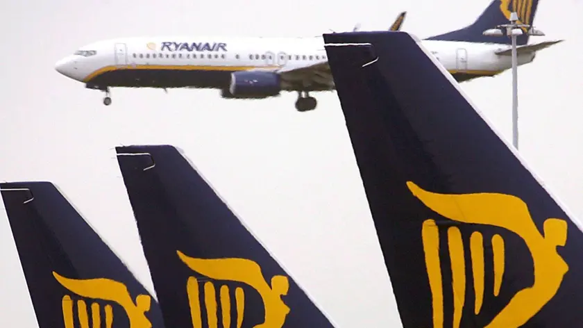 Un aereo della compagnia Ryanair in volo e altri fermi sulla pista