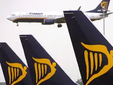 Un aereo della compagnia Ryanair in volo e altri fermi sulla pista