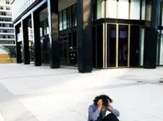 Overwhelmed young businessman sitting on sidewalk --- Image by © Mango Productions/Corbis