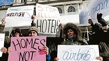 epa04571225 Detractors of Airbnb operations in New York hold signs during a rally at City Hall before a hearing on the subject of Airbnb in New York, New York, USA, 20 January 2015. The New York City Council was holding a hearing today called 'Short Term Rentals: Stimulating the Economy or Destabilizing Neighborhoods?' which was meant to examine the issue of short term rentals as handled by Airbnb. EPA/JUSTIN LANE