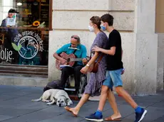 epa08628711 People with face masks pass by a street singer and his dog in Zagreb, Croatia, 27 August 2020. During the last days the pandemic of the COVID-19 coronavirus is in expansion in Croatia with more than 200 infected people on 26 August. EPA/ANTONIO BAT