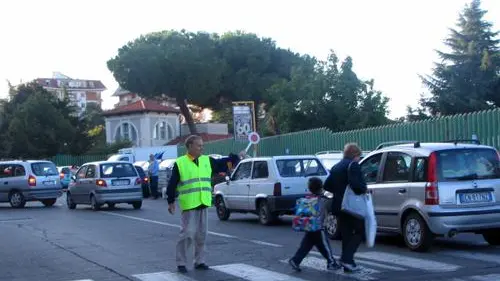 Un nonno-vigile davanti a una scuola