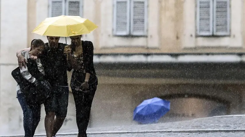 Persone si riparano con l'ombrello durante il violento temporale che ha colpito Roma, 17 giugno 2014. .ANSA/ANGELO CARCONI