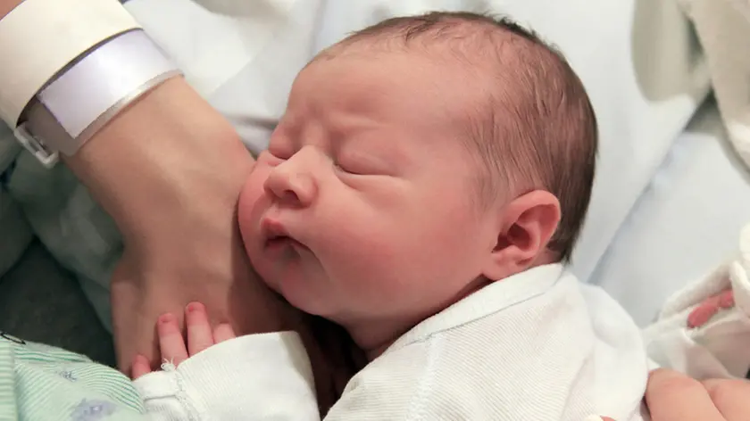 Sleeping newborn baby in the arms of my mother in hospital