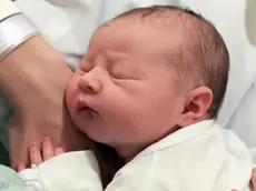 Sleeping newborn baby in the arms of my mother in hospital