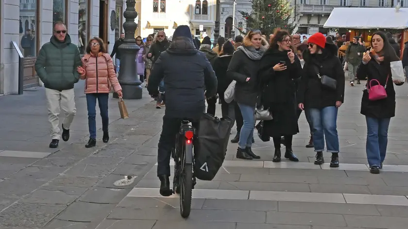 Un ciclista mentre pedala fra i pedoni in piazza della Borsa. Francesco Bruni
