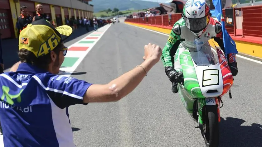 Valentino Rossi accoglie in ginocchio davanti al box il pilota italiano Romano Fenati (Ktm) che ha vinto il Gp d'Italia nella categoria della Moto3 sul circuito del Mugello, 1 giugno 2014. ANSA/UFFICIO STAMPA SKY SPORT ++ NO SALES, EDITORIAL USE ONLY ++