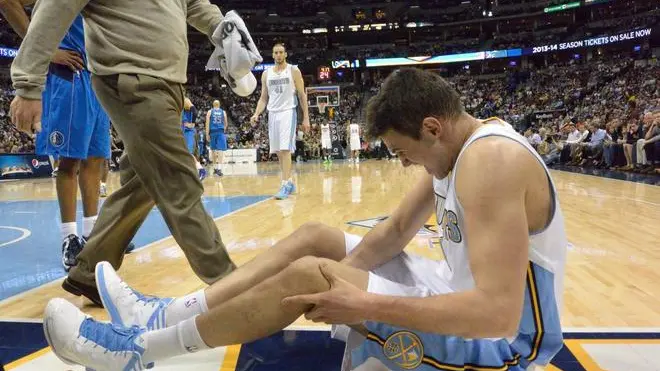 Denver Nuggets Forward Danilo Gallinari of Italy holds his knee after landing awkwardly as Nuggets medical staff assists during the first half of their NBA game against the Dallas Mavericks at the Pepsi Center in Denver, Colorado, USA, 04 April, 2013. Gallinari was helped from the court after the injury. ANSA/BOB PEARSON CORBIS OUT