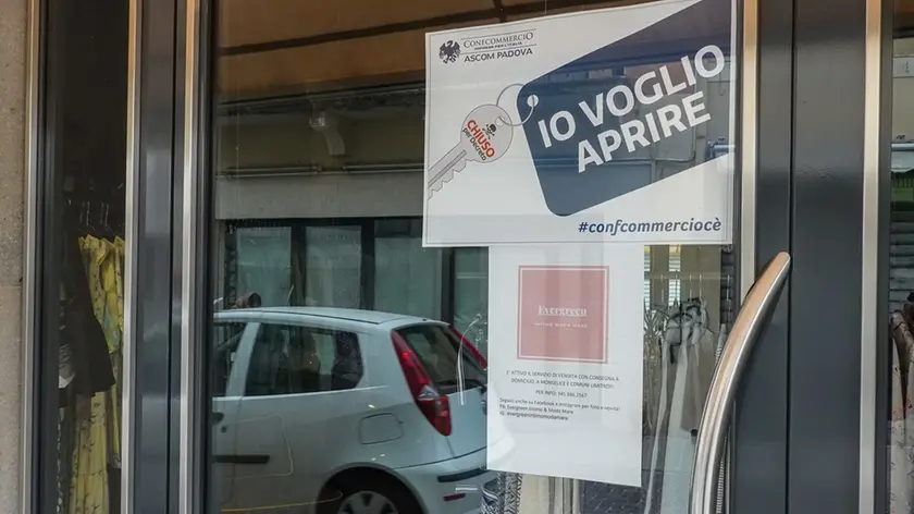 Un cartello di protesta affisso sulle vetrine di un negozio di vestiti