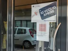 Un cartello di protesta affisso sulle vetrine di un negozio di vestiti