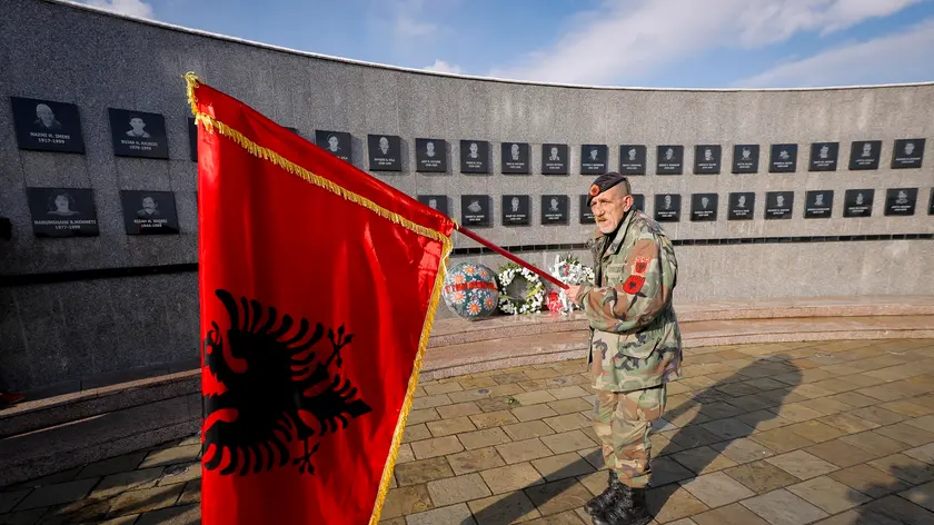 Un uomo con una bandiera albanese rende omaggio ai kosovari uccisi dalle forze serbe in un cimitero di Racak (foto d'archivio)