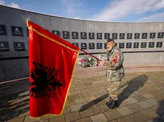 Un uomo con una bandiera albanese rende omaggio ai kosovari uccisi dalle forze serbe in un cimitero di Racak (foto d'archivio)