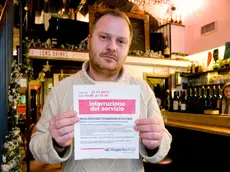 Il titolare della Taverna del Ghetto mostra l'avviso rifoerito al distacco dell'elettricità (foto Silvano)