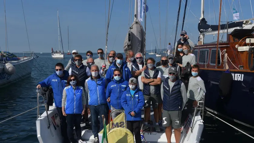 L'equipaggio di Venni Vind con la mascherina, sotto i ragazzi volontari dell’Istituto Nautico che si occupano degli ormeggi