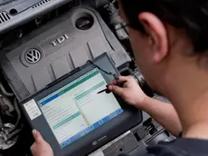 Un tecnico con un apparecchio di diagnosi elettronica controlla una vettura Volkswagen