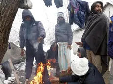 epa08043985 Migrants warm themselves by the fire in front their tent during a snowy winter day at the Vucjak refugee camp outside Bihac, northwestern Bosnia and Herzegovina, 04 December 2019. Hundreds of migrants remain at the camp even after international officials called for it to be shut down due to lack of facilities. EPA/FEHIM DEMIR