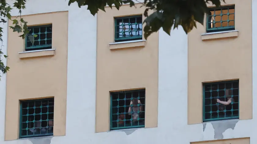 Detenuti affacciati alle finestre durante la protesta. In alto gli agenti della Penitenziaria. Foto Lasorte