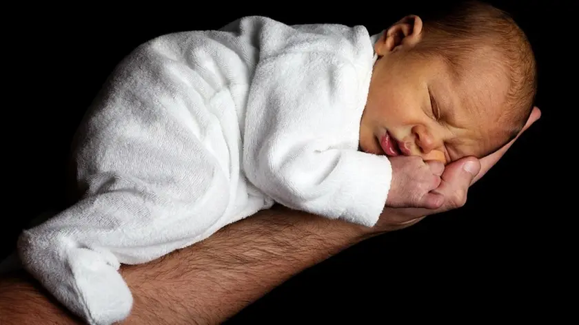 Un neonato tenuto in mano dal suo papà