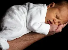 Un neonato tenuto in mano dal suo papà