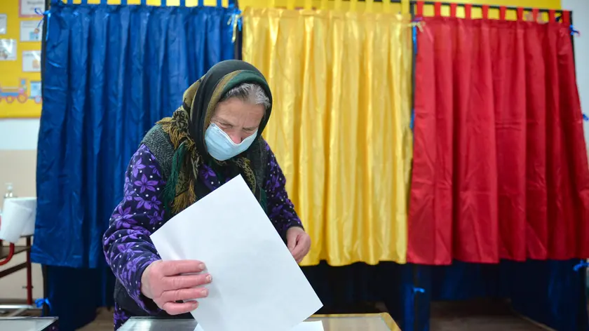 An elderly woman casts her vote in the village of Sabareni, Romania, Sunday, Dec. 6, 2020. Voting started in Romania's legislative election expected to restore some measure of stability after five years of political and social turbulence with more than 18 million Romanians registered to vote for a new legislative body. (AP Photo/Alexandru Dobre)