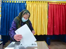 An elderly woman casts her vote in the village of Sabareni, Romania, Sunday, Dec. 6, 2020. Voting started in Romania's legislative election expected to restore some measure of stability after five years of political and social turbulence with more than 18 million Romanians registered to vote for a new legislative body. (AP Photo/Alexandru Dobre)