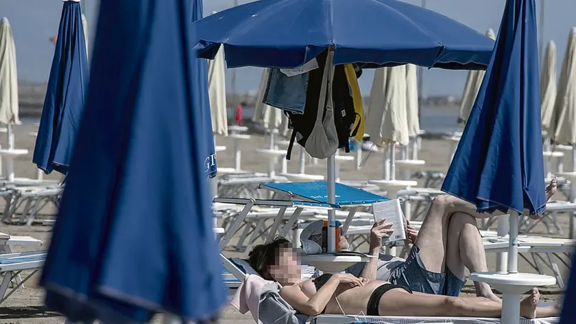 La spiaggia di Grado con le sue file di ombrelloni e gli alberghi a due passi. Foto Katia Bonaventura. Sotto la zipline tra i boschi e il lago di Sauris e i tavolini di un bar affollato sulla spiaggia di Lignano. Nella foto grande a destra uno scatto della