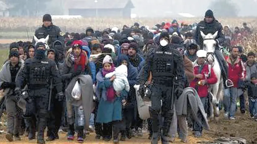 Escorted by police, migrants move through fields after crossing from Croatia, in Rigonce, Slovenia, Tuesday, Oct. 27, 2015. The European Union is lashing member countries for dragging their feet on providing funds and experts to help manage Europe's biggest refugee emergency in decades. (ANSA/AP Photo/Darko Bandic)