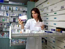 Beautiful female model pharmacist looking at medicine