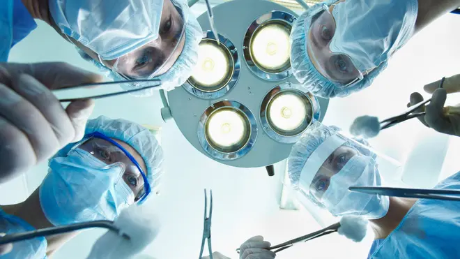 Low angle view of four surgeons bending over the patient during operation