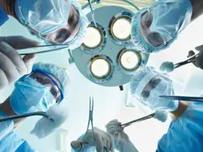 Low angle view of four surgeons bending over the patient during operation