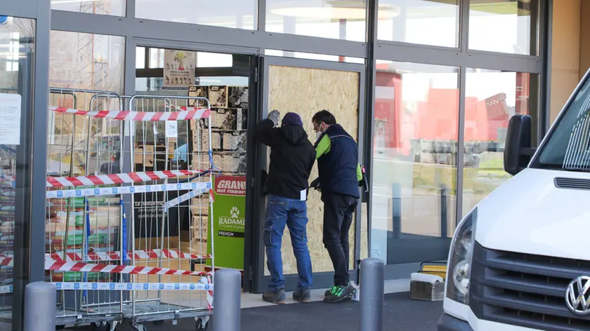 Gli operai al lavoro per chiudere con un pannello la porta sfondata la notte scorsa dai ladri. Foto Bumbaca