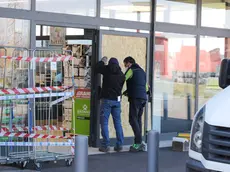 Gli operai al lavoro per chiudere con un pannello la porta sfondata la notte scorsa dai ladri. Foto Bumbaca