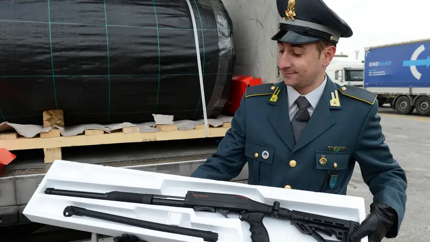 Un militare della Guardia di Finanza mostra alcune delle armi sequestrate a Trieste